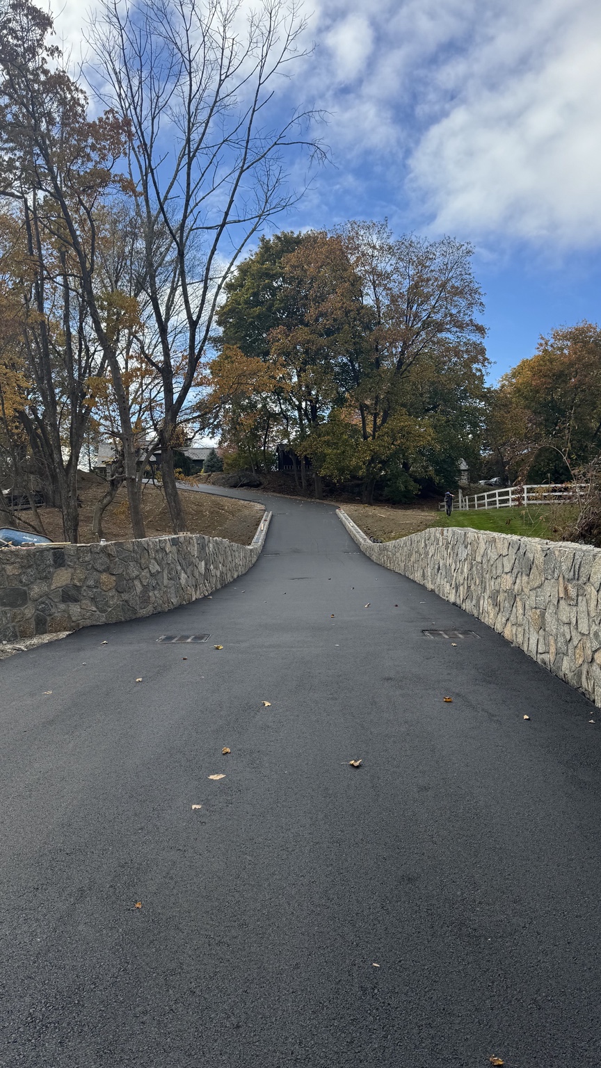 Blacktop driveway with stone walls